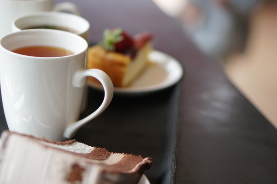 Chocolate Cake and cheese cake with strawberry on plate. Cup of tea during evening English tea time. Selective focus