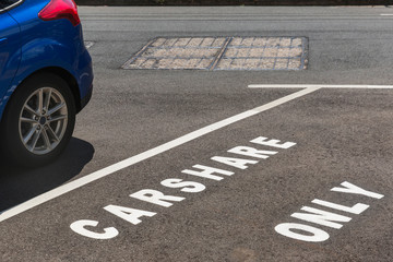 Carshare only road sign on inner city asphalt parking space.
