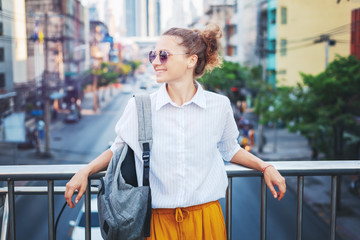 Portrait of a cute stylish young girl on the background of a big city. Urban style, fashion, travel, lifestyle.