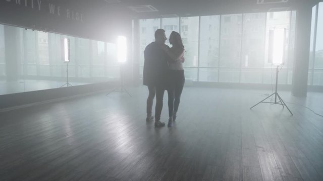 Couple dancing in a dance studio and young woman performs splits. Practicing new kizomba moves.
