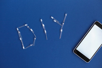 DIY word from diode and phone on a blue background. DIY words for Do It Yourself concept. place for...
