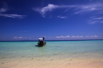 Isolated longtail boat bow on turquoise shallow water under blue sky with few cirrus clouds on tropical island Ko Phi Phi, Thailand
