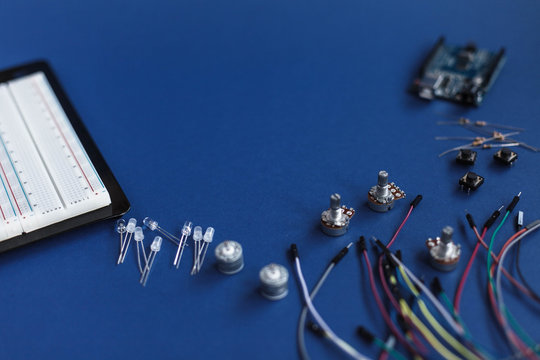 DIY electronic kit on the blue background, FLAT LAY, variety of sensor and tools with copy space: Arduino board, button, potentiometer, resistors for the development