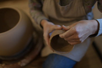Fototapeta na wymiar Female potter works with ceramic at his workshop. Young woman work inside 