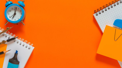 Back to school. Pattern of modern design with school supplies pencils, felt-tip pens, alarm clock, notebook copy space, school mock-up poster on an orange coral blackboard background long banner
