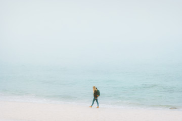 Traveler woman walking on beach Traveling alone lifestyle vacations outdoor foggy sea scandinavian nature