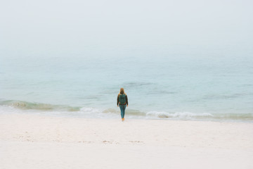 Woman traveler walking alone on foggy ocean beach Travel Lifestyle wanderlust  adventure vacations outdoor