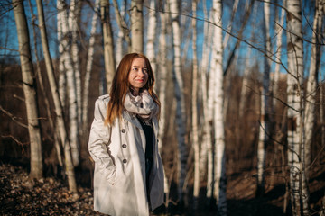 Portrait of a girl on the background of trees in early spring at sunset.