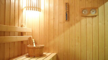 Sauna interior room. Classic wooden sauna with light, thermometer and hourglass on wall. Relax in...