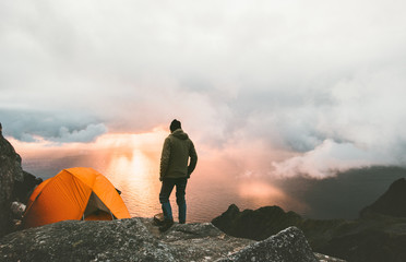 Man traveling with tent camping on mountain top outdoor adventure lifestyle  hiking active extreme summer vacations sunset and clouds view - obrazy, fototapety, plakaty