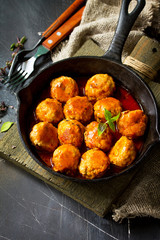 Homemade Beef meatballs in tomato sauce in a frying pan on dark stone table.  Copy space.