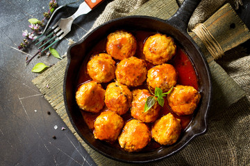 Homemade Beef meatballs in tomato sauce in a frying pan on dark stone table.  Flat lay, top view background. Copy space.
