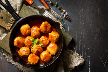 Homemade Beef meatballs in tomato sauce in a frying pan on dark stone table.  Flat lay, top view background. Copy space.