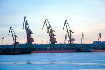 Fototapeta premium Żurawie portowe w porcie rzecznym w zimowy dzień. Port zimowy.