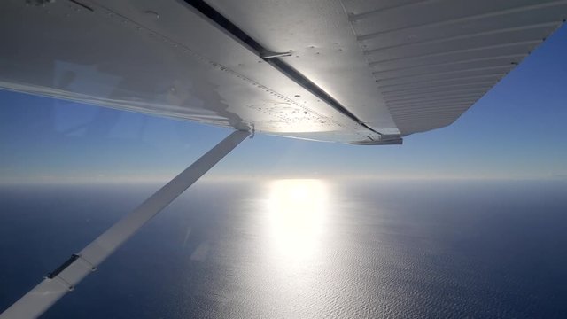 Seaplane flying over tropical sea in bright sunshine