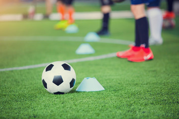 football between marker cones on green artificial turf with blurry soccer team training