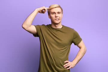 blonde frustrated angry sad man with hand on his hip points at head. close up photo. isolated...
