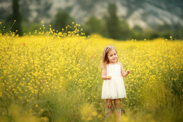 Fototapeta premium A Happy family: mother with young girl stand hand in hand on a green field against the background of coniferous forest and mountains.