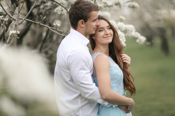 Fototapeta premium A Kissing newlywed couple spending time in blooming garden.