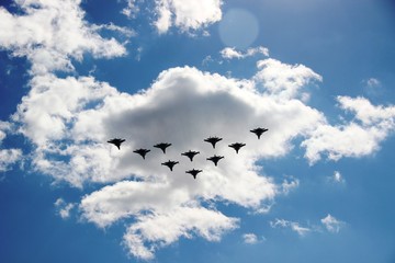A group of ten aircraft in a blue sky with white clouds. Ten planes in a blue sky with clouds on a Sunny day, selective focus