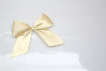 Gold satin ribbon bow on bright white background