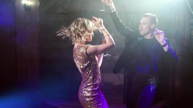 Young attractive couple dancing and drinking wine at a party.