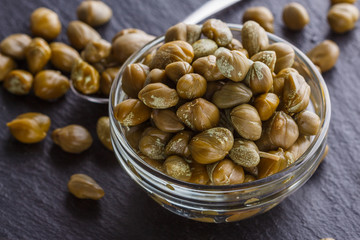 pickled capers on a dark stone background