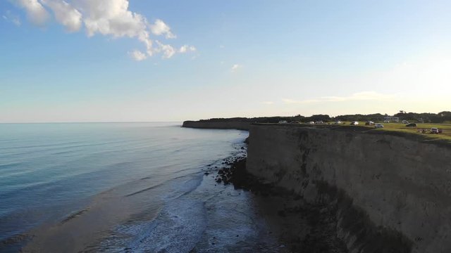 Aerial rising 4K drone shot, parallel to the cliff coast, full of cars parked on the edge, on a sunny afternoon in Mar del Plata, Argentina.