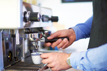 Clsoe-up shot of barista hands while brewing espresso coffee