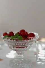 plate with red cocktail tomatoes decorated with basil on a table beige background copy space