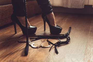 woman black high heels and sex toys. Sexy woman fetish pumps and whip, bdsm concept - obrazy, fototapety, plakaty