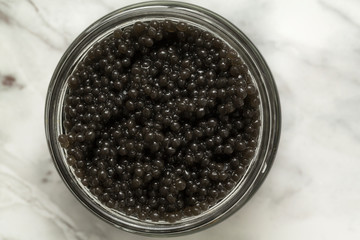 Jar with delicious black caviar on grey background. Top view