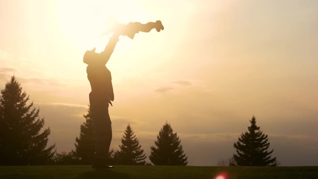 Father having fun with daughter silhouette. Father lifting up his daughter in the park while sunset.