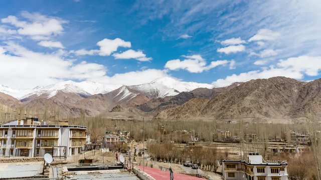 4K Timelapse of cityscape and high snow mountain range on rural desert landscape and temple with beautiful blue sky and amaizing cloud moving as background, viewed of rooftop Leh, Ladakh, India.