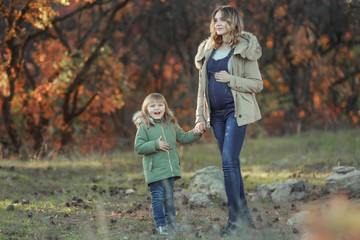 A pregnat Mother hugging her child during walk in the park