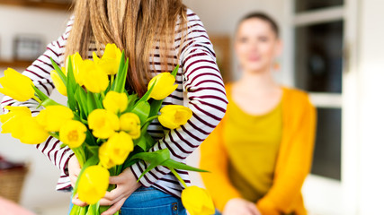 Happy Mother's Day or Birthday Background. Adorable young girl surprising her mom with bouquet of...