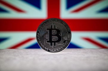 Physical silver version of Bitcoin BTC and United Kingdom Flag on the background. Conceptual image for investors in cryptocurrency and Blockchain Technology