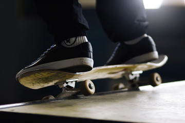 A man in black pants and black sports shoes on a skateboard does a slip-on trick on a ramp in the...