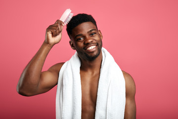 Shower time concept. Macho with white towel on his neck brushing his hair, expresses positive emotions. happiness, Good morning