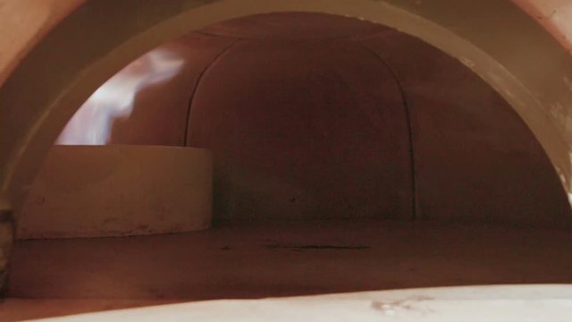 Moving inside empty commercial wood fired stone pizza oven. Dolly shot entering inside mouth of oven with internal refractory core for cooking Panzerotti, Stromboli or Calzones.