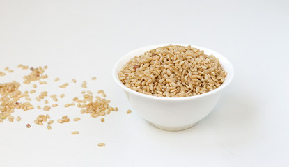 Bowl of long grain brown rice isolated on white background