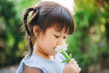 Smell sensory learning from flower. Cute Asian kid exploring natural environment through outdoor...
