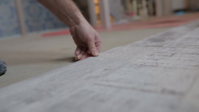 The builder is engaged in laying laminate in the room - repair and finishing work