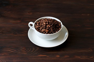 Coffee cup and coffee beans on wooden background.