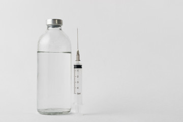 medical drugs and beauty products in glass jars for injections with a syringe with a needle on a white background