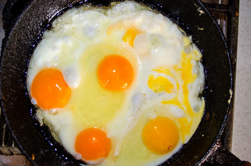 Appetizing fried five eggs cook in an old vintage cast iron skillet