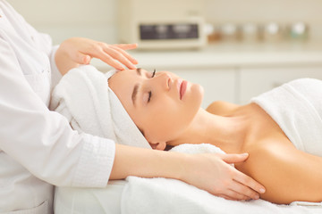 Fototapeta na wymiar Facial massage for a young woman lying in a beauty salon.