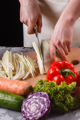 young woman in a gray apron cut cabbage