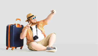 Fat funny man a suitcase smiling goes on a gray background.