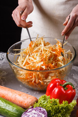 a young woman in a gray apron mixes a salad of cabbage